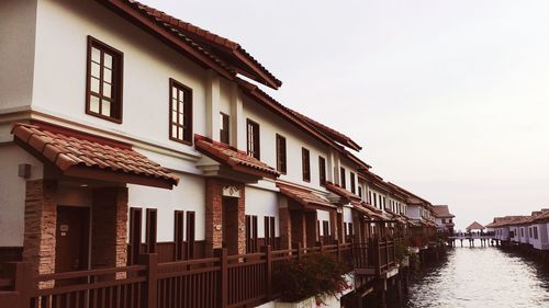 Residential buildings by river against sky