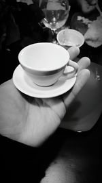 Close-up of hand holding coffee cup on table