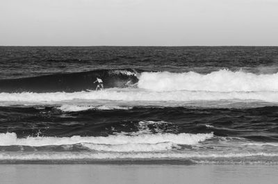 Man surfing over waves against clear sky