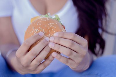 Midsection of woman holding hamburger