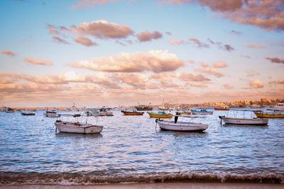 Boats moored in sea against sky during sunset