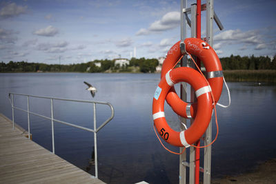Red railing by lake against sky