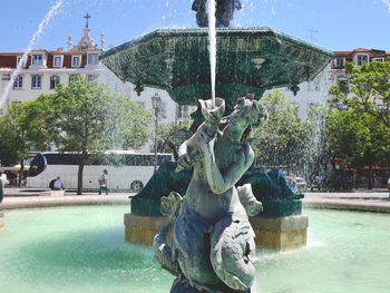 Fountain in city against sky