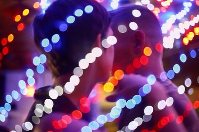 Illuminated colorful defocused lights against man and woman in bar