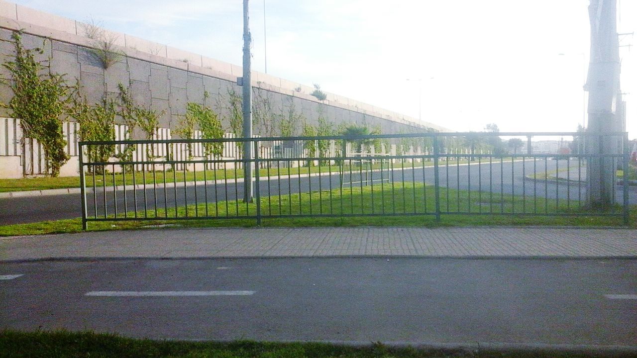 built structure, architecture, fence, grass, sky, clear sky, protection, railing, safety, building exterior, metal, day, security, field, outdoors, no people, tree, chainlink fence, plant, sunlight