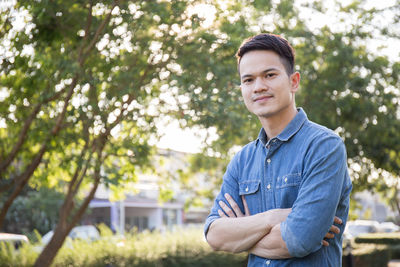 Portrait of man with arms crossed standing in park