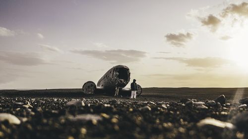 Surface level of abandoned vehicle on field against sky