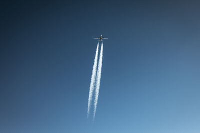 Low angle view of airplane flying against clear blue sky