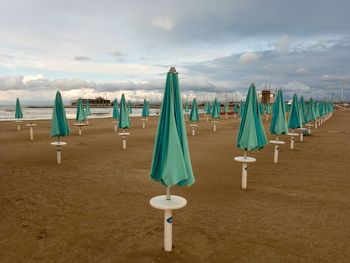 Deck chairs on sand at beach against sky