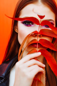 Close-up portrait of young woman holding leaves against face