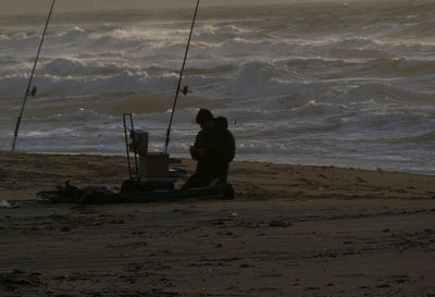 Man fishing at beach against sky