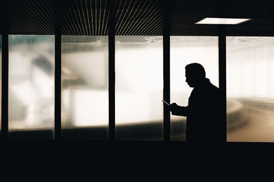 Silhouette man standing against window in building