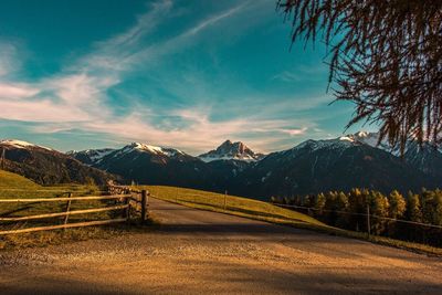Road on field with mountains against sky