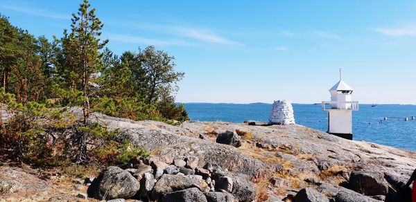 Lighthouse on rock by sea against sky