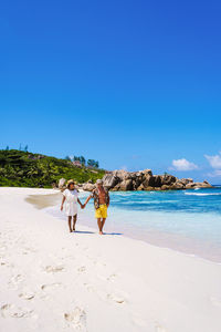 People at beach against clear blue sky