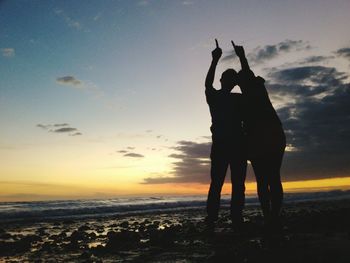 Silhouette couple gesturing at beach during sunset