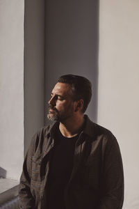 Mature man with eyes closed against white wall