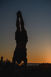 Man doing handstand against clear sky during sunset