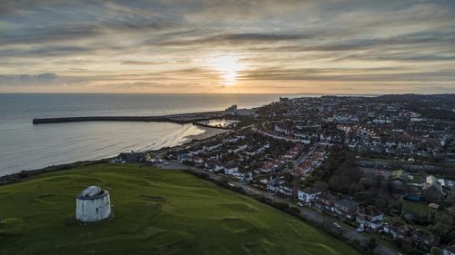 High angle view of city by sea against sky during sunset