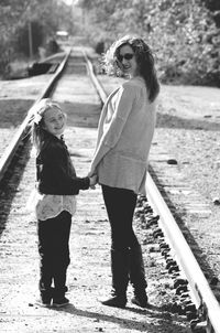 Full length of smiling young woman standing on railroad track