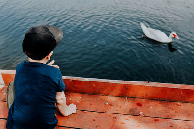 Rear view of boy sitting on boat against sea