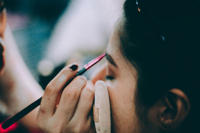 Cropped hand of woman applying make-up on woman face