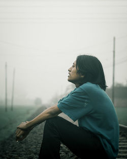 Side view of young man sitting on track