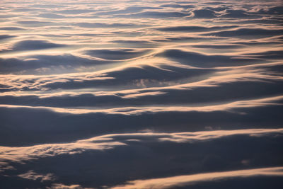 Full frame aerial shot of dramatic clouds resembling ocean waves during sunrise