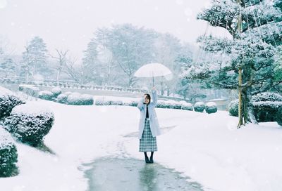 Woman standing on snow covered trees during winter