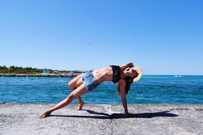 Full length of woman on beach against clear blue sky