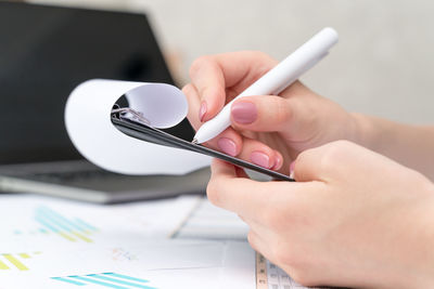 Midsection of person holding paper with text on table