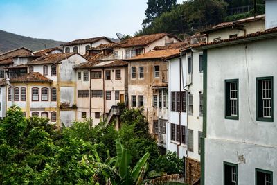 Houses and trees in city against sky