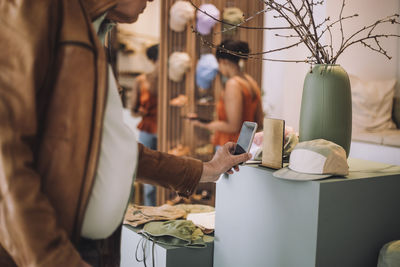 Midsection of senior man scanning qr code through smart phone at fashion clothing boutique