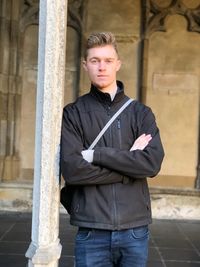 Portrait of young man standing against building