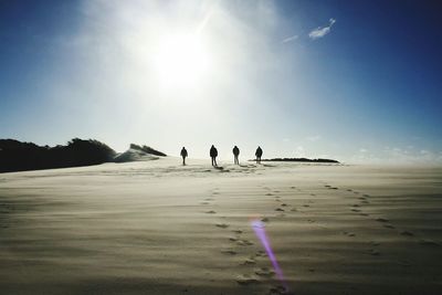 Silhouette people standing on desert against sky