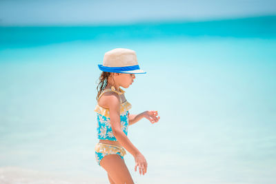 Full length of woman wearing hat at beach against sky