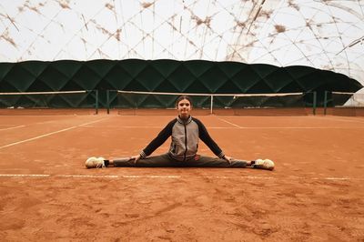Full length of woman doing split on field