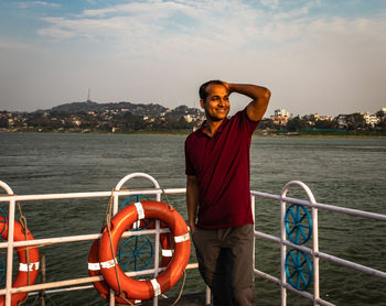 Portrait of man standing by railing against sea