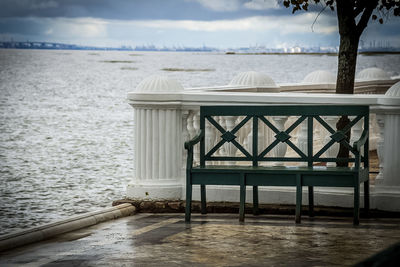 Chair on table by sea against sky