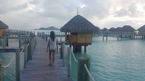 Rear view of woman standing on pier over sea