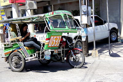 Woman sitting in jinrikisha on city street