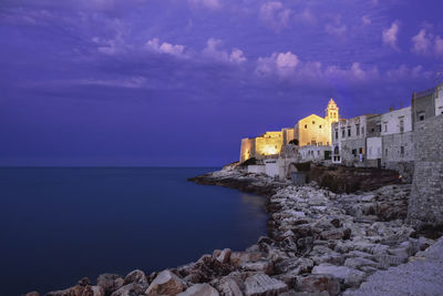 Buildings by sea against sky
