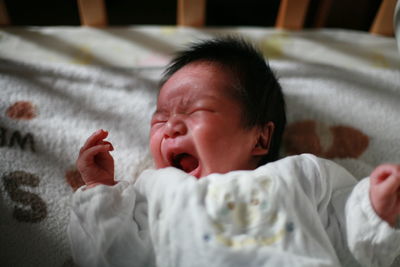 High angle view of baby boy crying while lying in crib at home