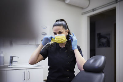 Female dentist putting protective face mask on