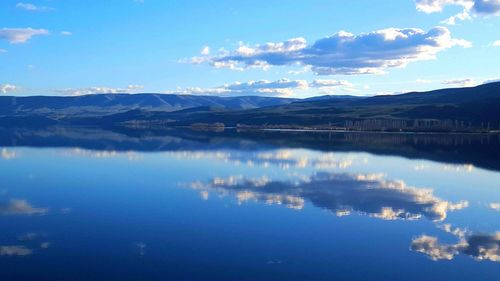 Scenic view of lake by mountains against sky