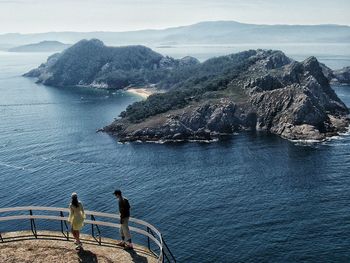 High angle view of man and woman at observation point by sea