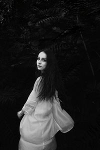 Portrait of smiling young woman standing against tree