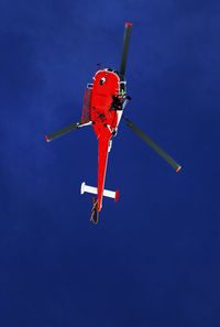 Low angle view of helicopter flying against blue sky