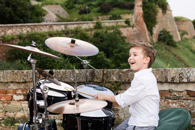 Smiling boy playing drum kit outdoors