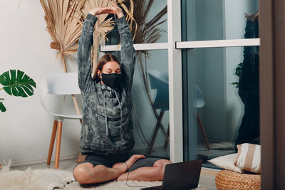 Woman with arms raised sitting at home